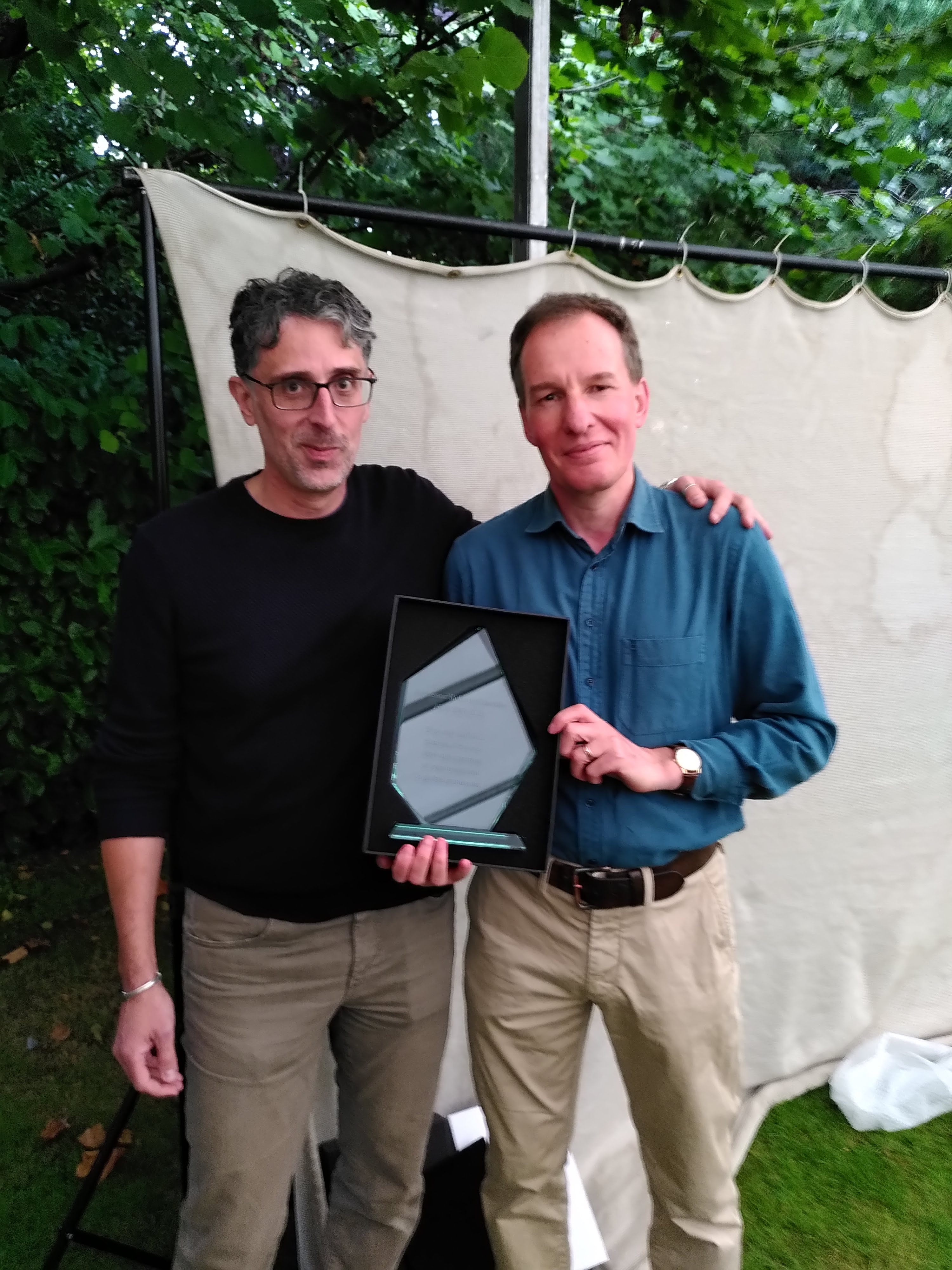 Richard Chandler on the right holding a plaque and Gianluca Baio on the right.